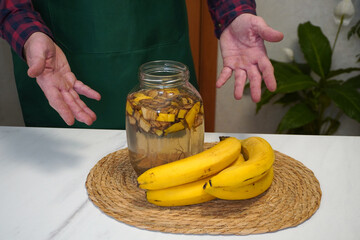 Gardener showing banana peel fertilizer in jar with fresh bananas