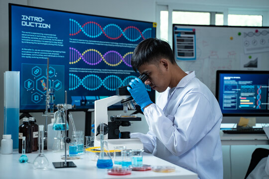 Asian scientist wearing lab coat and gloves using a microscope in a high tech laboratory focused on DNA research biotechnology healthcare and scientific innovation