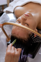 Close-up of a woman receiving a relaxing Japanese head spa treatment, with green massage sticks...