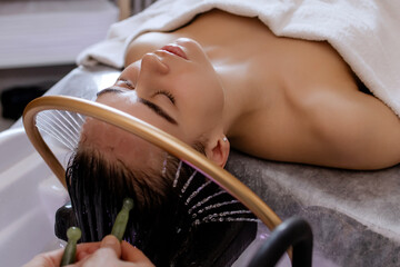 Close-up of a woman receiving a relaxing Japanese head spa treatment, with green massage sticks...