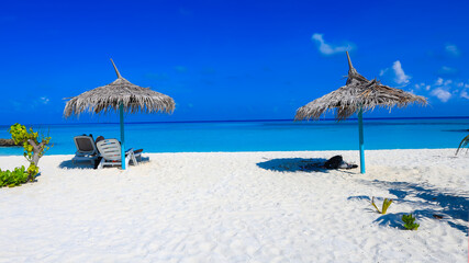 Summer tropical with white umbrella on the beach with  blue sky background