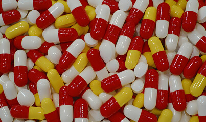 Assorted pills red/white, yellow/white, and white tablets are piled together in a bulk