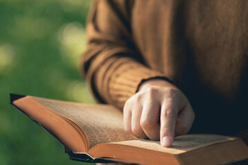  Christian Bible Study Concepts. close up woman's hand holding and reading a book on a Sunny morning. Studying the word of God. Sharing the gospel. Followers studying the word of God. Education