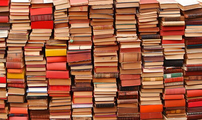 Stacked books, creating a textured wall, various colors and sizes. Many pages visible