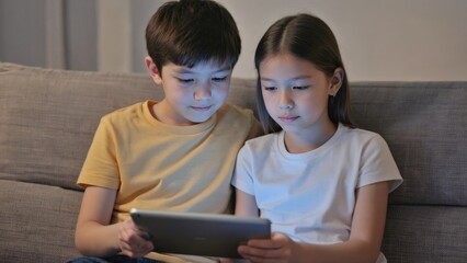 Two children enjoying tablet together. Modern lifestyle with digital devices.