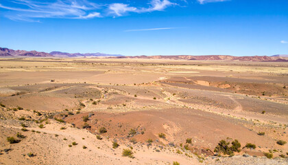 vast desert landscape showcases rolling hills and arid terrain under clear blue sky, evoking sense of tranquility and isolation. expansive view highlights natural beauty of desert environment