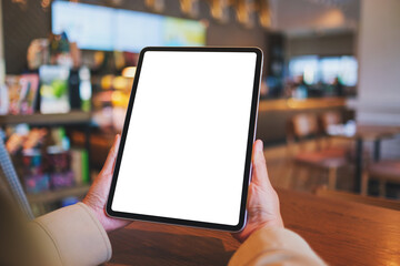 Mockup image of a woman holding digital tablet with blank white desktop screen in cafe