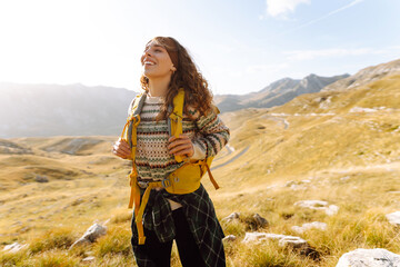 Rear view of joyful tourist in hiking clothes feeling freedom with mountain view. Young woman hiker...