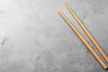 A single handcrafted bamboo chopstick rests diagonally on a light gray textured surface, showcasing its natural grain and artisanal quality, perfect for display