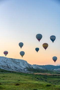 Hot air balloons flying over Pamukkale travertines at sunrise