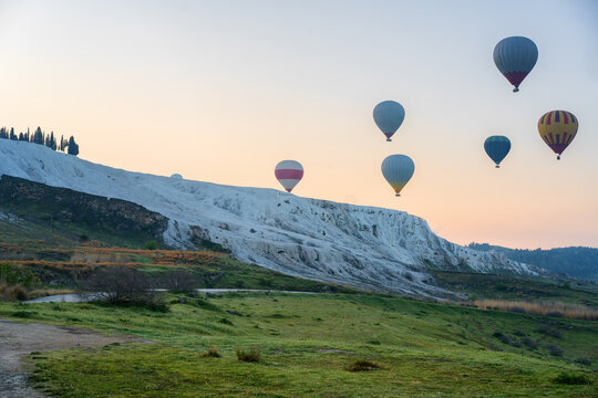 Hot air balloons flying over Pamukkale travertines at sunrise