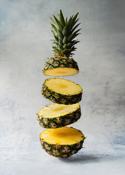 Floating slices of juicy pineapple fruit on light background.
