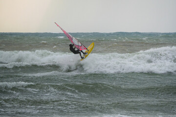 Water Sport Activity - Windsurfer Riding a Wave in Rough Sea on a Windy Day