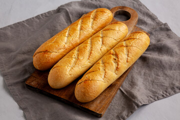 Homemade French Baguette with Garlic Filling on a wooden board, side view.