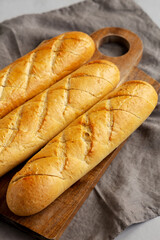 Homemade French Baguette with Garlic Filling on a wooden board, side view.