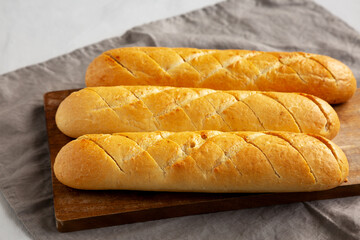 Homemade French Baguette with Garlic Filling on a wooden board, side view.