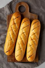 Homemade French Baguette with Garlic Filling on a wooden board, top view.