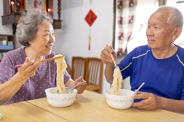 Happy Asian Elderly couple eating noodles at home