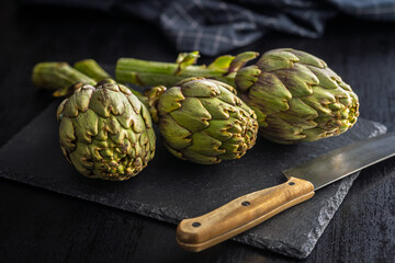 Fototapeta premium Ripe artichokes plant on cutting board.
