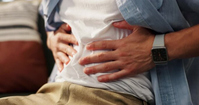 Hands, tummy ache and man on sofa in home for indigestion, diarrhea or food poisoning. Illness, sick and male person with stomach pain for constipation, IBS or abdominal muscle strain in house.