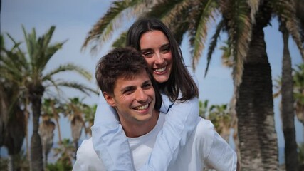 A joyful couple enjoying a playful moment together as the woman gives a cheerful piggyback ride to her partner, radiating happiness and affection in their delightful interaction.