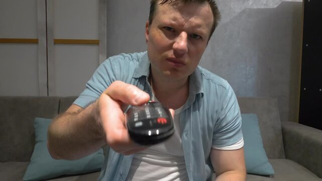 A man nervously switches channels with a TV remote control, throw away the TV remote control. Angry man. Slow motion