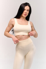 Fototapeta premium Smiling sporty woman in white underwear posing on studio background with copy space. Female beauty, sport, spa concept