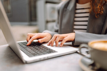 Beautiful woman in glasses with laptop working at table outdoors. Female freelancer with laptop in cafe enjoying weather. Technology concept, remote work.