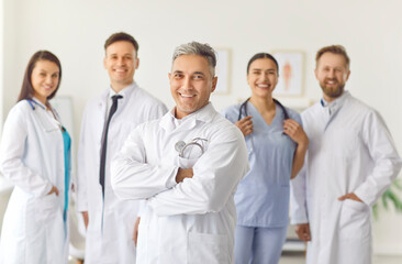 Fototapeta premium Portrait of a group of smiling doctors at the workplace, close-up. Professionalism and friendly cooperation. A team of confident medical specialists in the clinic, surgical department