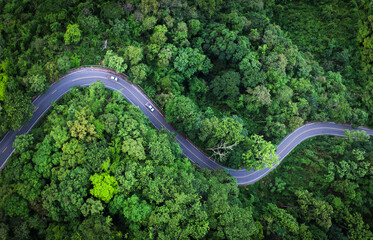 Electric cars to protect the environment and transportation road of Aerial view of a road in the middle of the forest , road curve construction up to mountain	