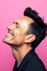 Fototapeta premium Pink solid background. A happy and poised man radiating charm. Conceptual art of style for aging men. Modish men's classic short back and sides haircut - midlife white man with black hai.