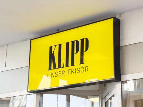 Bright yellow klipp unser frisor hair salon sign on modern building exterior