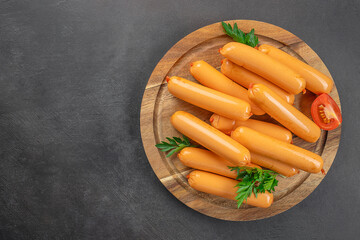 delicious boiled sausage on a wooden board, on a dark background. top view. copy space
