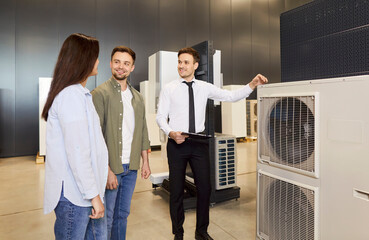 Male consultant or salesman helping couple of clients choose an HVAC system for home in a hardware...