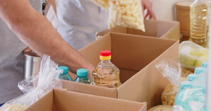 Close up shot of volunteers hands packaging food in boxes at a humanitarian aid center. Teamwork and dedication to charity and humanitarian efforts are evident as they work together.