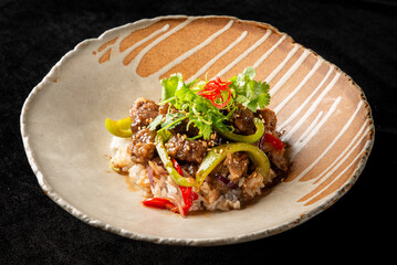A beautifully arranged plate of Asian-inspired dish featuring tender beef mixed with bell peppers and served over rice, garnished with fresh herbs and chili slices for added flavor.