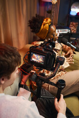 Operator shooting blogger on professional camera during podcast in studio