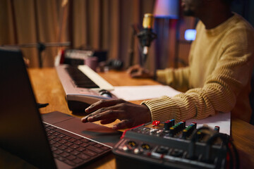 Man sitting at his workplace with laptop and mixing console and recording podcast in studio