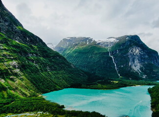 Lovatnet Lake in Norway during summer, with turquoise water, steep mountains, and a waterfall