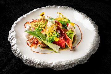 An elegant dish featuring grilled fish garnished with colorful vegetables, microgreens, and a drizzled sauce, beautifully arranged on a textured white plate for a refined dining experience.