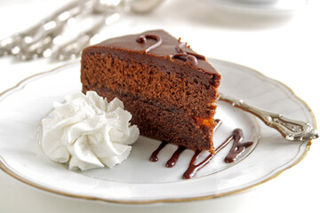 A piece of chocolate Sacher torte on a white plate