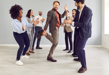 Young funny happy business people and company employees in suits dancing having fun and celebrate...