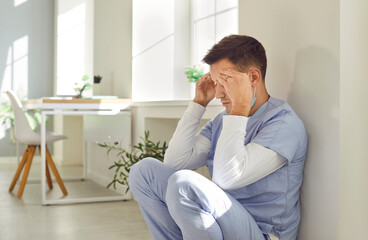 Stressed man nurse or doctor in blue scrubs feeling tired, exhausted and completely burnt out after...