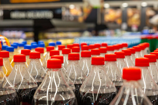  Rows of soda bottles with red caps on grocery store shelf, retail beverage display and consumer choice concept