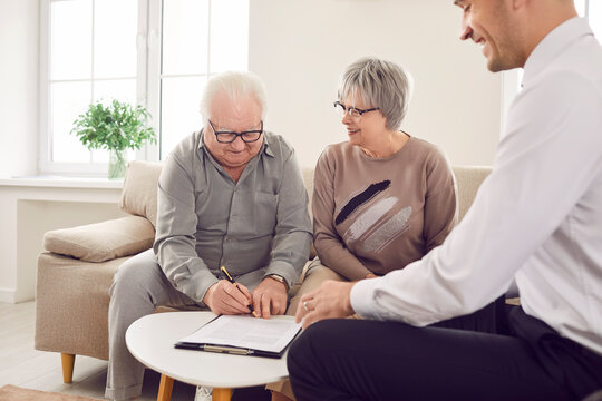 Happy elderly clients finalize decision by signing a contract with a trusted agent, adviser, or consultant. Satisfaction with the investment and insurance options discussed during the meeting.