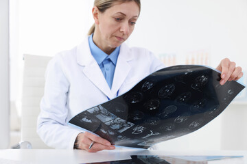 Doctor examining MRI scan at desk in hospital, closeup