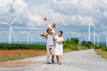 Happiness caucasian white family walking wind turbine farm while father piggyback of daughter together, environment and energy of sustainability, Happy family activity concept.