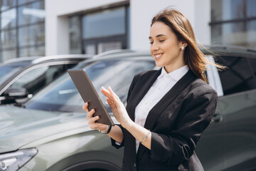 Saleswoman using tablet and working at car dealership