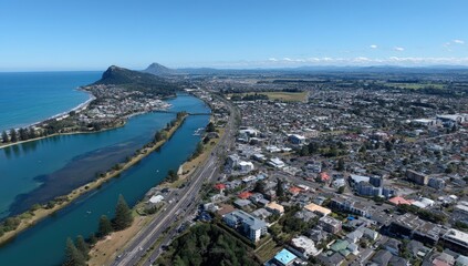 Fototapeta premium Aerial view of coastal city with mountains in the background and ocean shoreline.