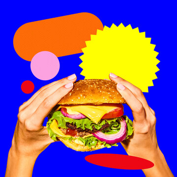 Two hands holding delicious burger with cheese, lettuce, tomato over blue background with abstract circles and cutouts. Concept of food, pop art, poster, ads. Contemporary art collage.